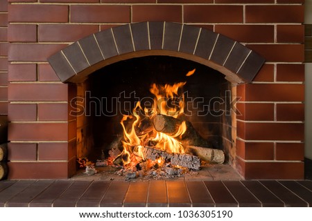 A brick fireplace in which a fire burns