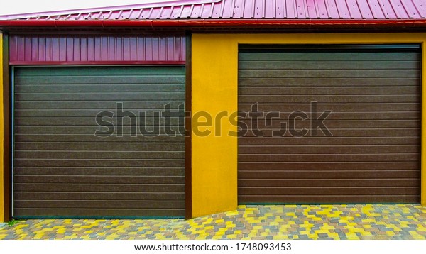 Brick\
garage with roller shutters for two cars in a residential district.\
Garage doors. New garage. Brown garage\
doors.