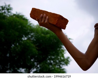Brick Holded On Hand By Asian Male Kid On Green Natural Background