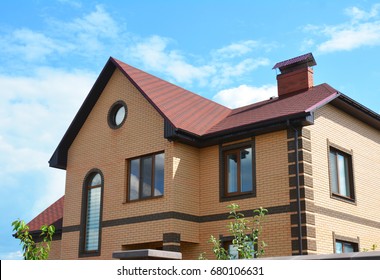 Brick house with attic window rain gutter system and red asphalt shingles roof.