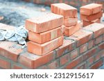 Brick house wall constuction with stack of red bricks. Building house brick wall concept.