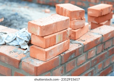 Brick house wall constuction with stack of red bricks. Building house brick wall concept.