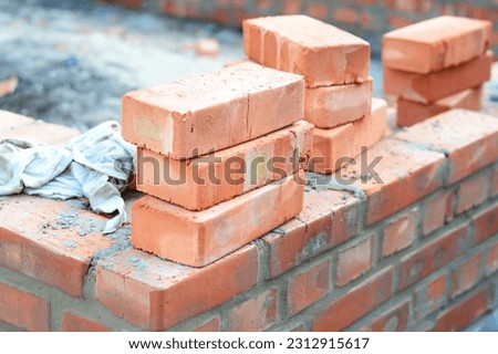 Brick house wall constuction with stack of red bricks. Building house brick wall concept.