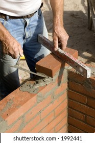 A Brick Layer Putting Down Another Row Of Bricks