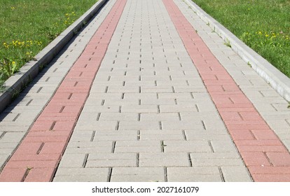 Brick Path Or Sidewalk With Perspective Going Into The Distance With Soft Sunlight Reflecting Of The Bricks. Long Paved Brick Footpath Outside With Grass.