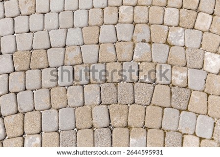 A brick patterned floor with a gray and tan color scheme. The pattern is made up of small square tiles