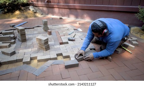 A brick paver artisan sets bricks into position for cutting for a two tone hardscaping design.