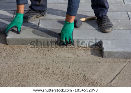 Brick Paver Working. Worker lay paving tiles, construction of brick pavement. Architecture background
