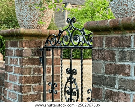 Brick Posts Supporting Potted Plants That Frame a Wrought-Iron Gate