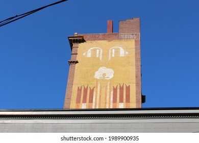 Brick structure with chimney and artwork resembling a face on a rooftop