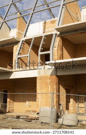 brick structure with steel frame and triangular roof bays illuminated by late sunlight exposed blockwork, metal connectors