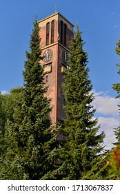 brick tower with a clock on a background of sky and trees