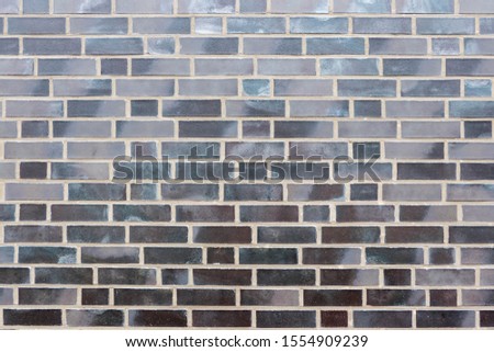 A brick wall in anthracite and brown brick with different shades of colour and white joints as background or texture.