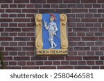 Brick wall with colorful sculpted tablet (gable stone) depicting an armored knight  with 1625 inscription in Haarlem, Netherlands, October 2024.