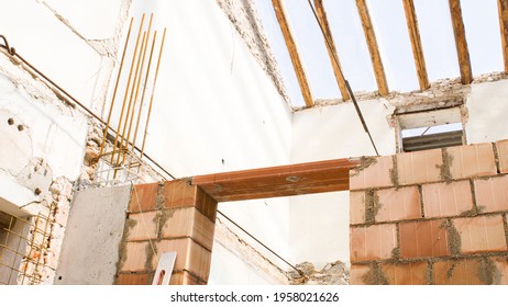 brick wall of a construction site with wooden beams of the roof in the background