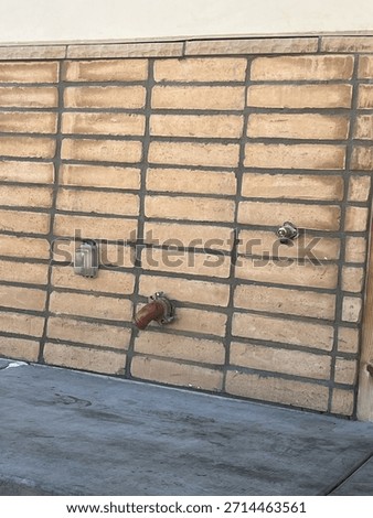 A brick wall with a hose bibb