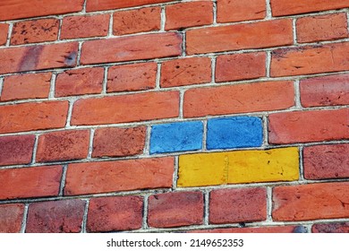 The brick wall is painted in the colors of the Ukrainian flag. Part of the wall of a 19th century building made of old red brick. Urban background with beautiful shape in architecture. Horizontal phot