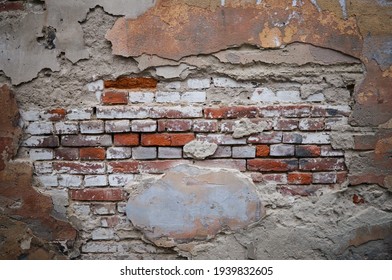 Brick wall with pieces of plaster. Wall of an old building in need of renovation. Aged wall texture of  brick building close up. Grunge background with red and white blocks and layers of cement stucco