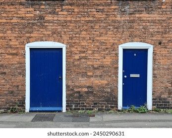 Brick wall texture with two blue doors. Red grunge brick wall, abstract background texture with old dirty and vintage style pattern.