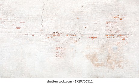 Brick wall texture with white shabby stucco, plaster. Red  and white brickwall background, white stonewall surface. Plastered wall with white uneven stucco with cracks and damages.