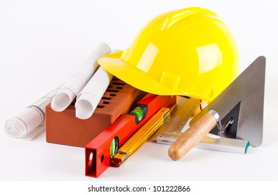 Brick, Yellow Hard Hat, Tools And Construction Plans On White Background