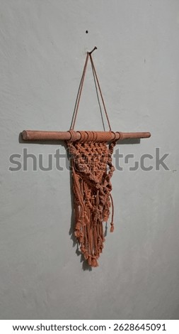 Brick-colored handmade macrame wall hanging decor with boho knots, displayed on a light wall background. Perfect for rustic and minimalist interiors.