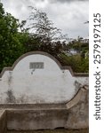 Bricked old bench beside a church. Written year 1899. Greenery in the background. Cloudy sky. Funchal, Madeira, Portugal.