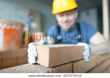 Bricklayer builder worker laying brick wall of house