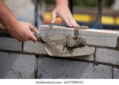 Bricklayer builder working laying red bricks and blocks on construction site