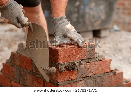 Bricklayer builder working laying red bricks and blocks on construction site