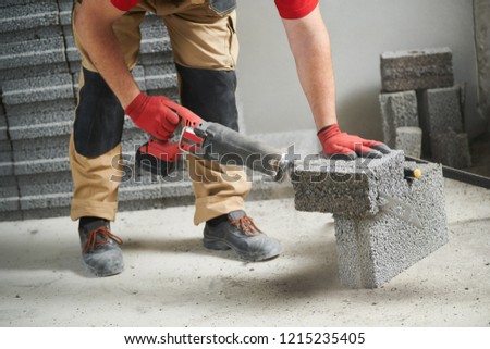 bricklayer cutting ceramsite concrete blockswith saw at walling