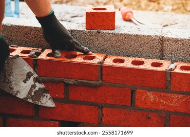 Bricklayer Expertly laying red bricks for a sturdy wall in a construction project in bright daylight