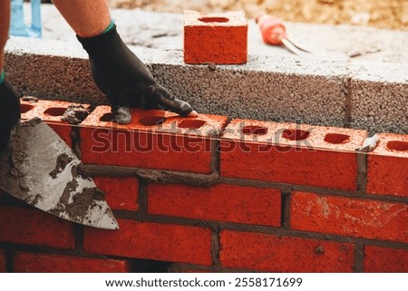 Bricklayer Expertly laying red bricks for a sturdy wall in a construction project in bright daylight