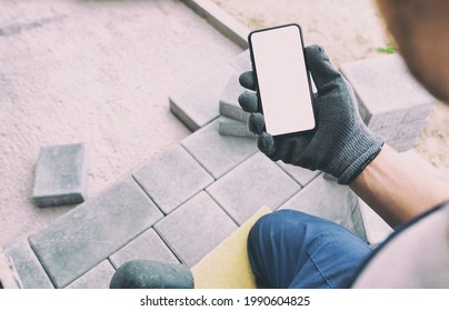 Bricklayer Holding The Phone With Blank Screen In Hand On Gloves.  Mockup For House Repair Or Building