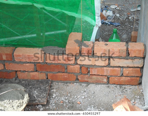 Bricklayer lay\
clay bricks block and stacked it together using cement mortar to\
form walls at the construction site.\

