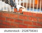 Bricklayer laying bricks. Crafting a sturdy brick wall with skilled hands in a construction site during the bright daylight hours