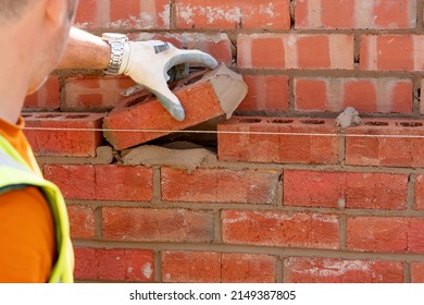 Bricklayer Laying Bricks On Mortar On New Residential House Construction, Last Brick To Fill The Gap