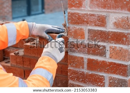 Bricklayer laying bricks on mortar on new residential house construction. Get construction qualification
