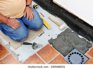 Bricklayer Laying The New Floor Tiles And A New Sewer In The Yard, Comprehensive Reform Of A House