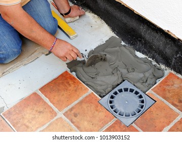 Bricklayer Laying The New Floor Tiles And A New Drain In The Yard, Comprehensive Reform Of A House