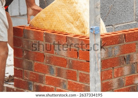 Bricklayer laying red bricks on building site