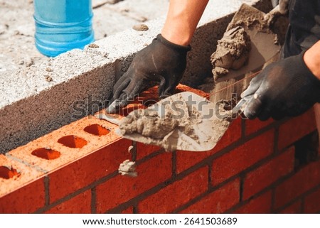 Bricklayer laying red bricks on building site