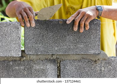 Bricklayer putting down another row of bricks in site - Powered by Shutterstock