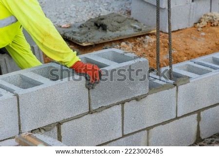 Bricklayer is putting down another row of cement blocks as part of construction process
