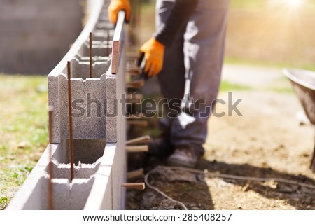 Bricklayer putting down another row of bricks in site