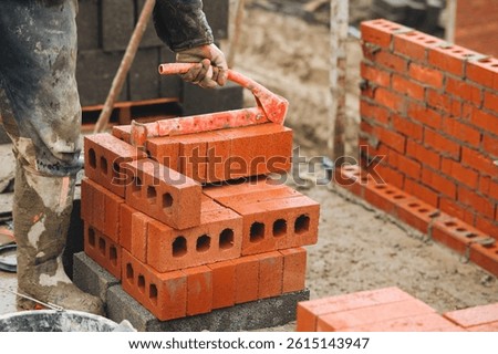 Bricklayer stacking bricks during building project at construction site in the afternoon, showcasing the labor and craftsmanship involved in masonry work