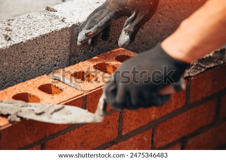 Bricklayer Using Trowel to Spread Mortar on Brick Wall