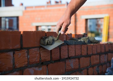 Bricklayer worker installing brick masonry on exterior wall. Professional construction worker laying bricks. - Shutterstock ID 1915924732