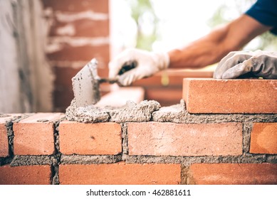 Bricklayer worker installing brick masonry on exterior wall with trowel putty knife - Shutterstock ID 462881611