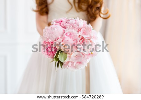 Bridal bouquet Beautiful of pink wedding flowers in hands of the bride. Close-up interior studio shot against bright background